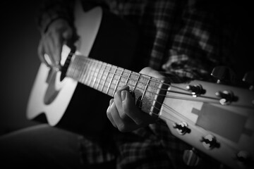 Woman playing guitar in darkness, closeup. Black and white effect