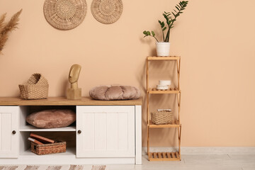 Interior of living room with shelving unit and home decor on commode near brown wall