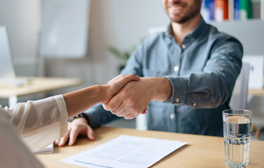 Cropped view of human resources manager shaking hands with successful vacancy applicant at office,...