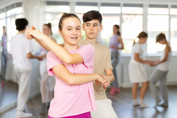 Obraz premium Girl dances Latin dance with male teenager partner during choreography lesson. Group training and rehearsal, preparation for competitions