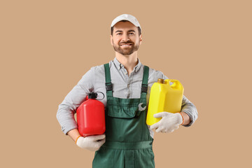 Male mechanic with canisters on beige background