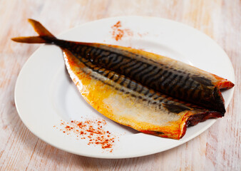 Appetizing hot smoked mackerel sprinkled with paprika served on white plate..