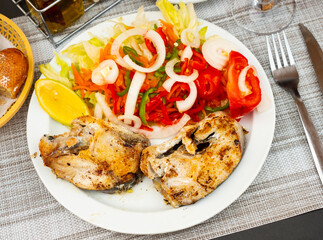 Hake fish fillets fryed granished with vegetable salat and lemon. Hake fillet in Spanish style.