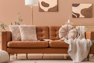 Interior of living room with brown leather sofa and paintings on wall