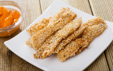 Healthy fast food. Delicious sesame crusted chicken fingers with sauce..