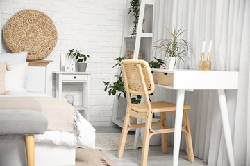 Interior of light bedroom with bedside table, shelving unit, table and big bed