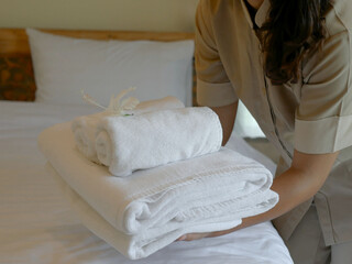 Hotel maid's hands place white flowers and towels on the bed in a luxury hotel room ready for guests who come to visit and want to rest