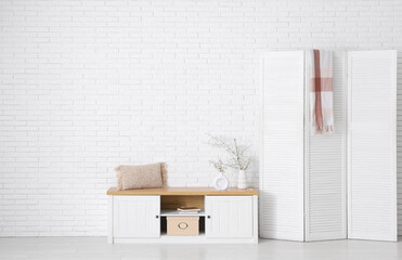 Interior of stylish room with folding screen and blooming tree branches on cabinet