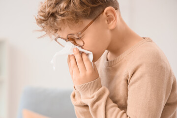 Sick little boy with tissue suffering from allergy at home, closeup