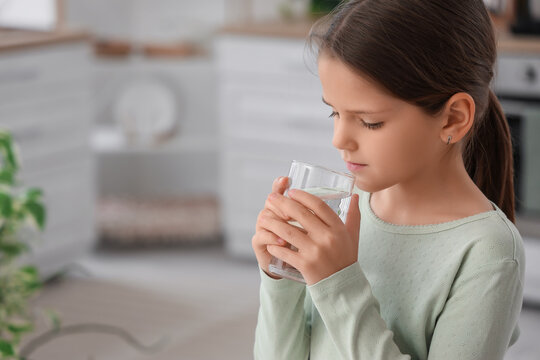 Cute girl drinking water in kitchen, closeup