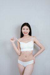Fototapeta premium Attractive young woman in lingerie posing in studio, showcasing slim waist, smooth skin, fit figure, and healthy lifestyle emphasis