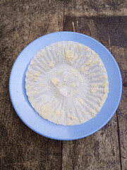 Bolu Kukus or steamed cake waste paper cases cup on blue plate isolated on wooden table. White cake paper cases cup