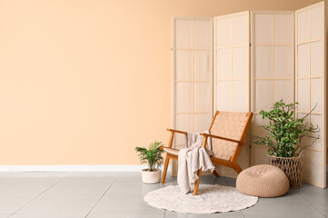 Interior of living room with wooden armchair, folding screen and plants
