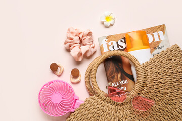 Fashion magazine with female summer accessories and mini fan on light pink background