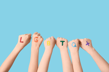 Naklejka premium Female hands with abbreviation LGBTQ+ on blue background
