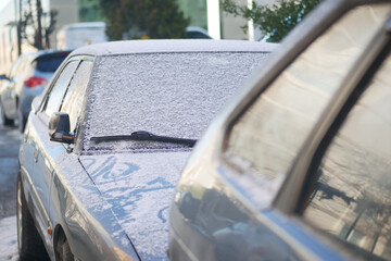 Snow covers parked cars on a cold urban morning in winter