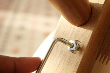 Close-up of hand adjusting furniture assembly with metal tool