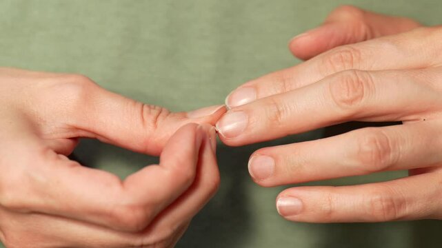 Close-up of a broken fingernail being picked with fingers illustrating concepts of nail care, fragility, and personal hygiene