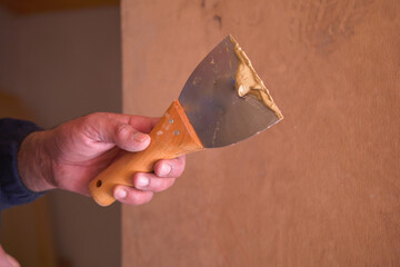 Skilled worker applies putty with a knife to a wood surface