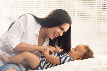baby and young mother playing and smiling in a brightly lit room