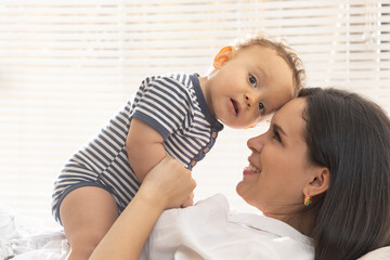 Young mother playing with her baby in a lighted room