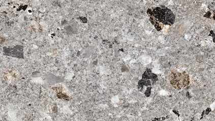 Gray stone surface with embedded, varied-sized rocks and flecks of color.  Close-up view of a speckled, textured material