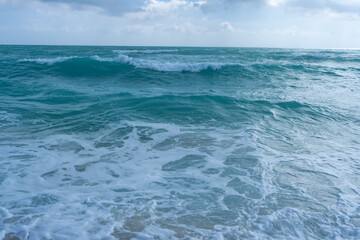 Turquoise sea water wave motion. Summer beach. Calm sea. Luxury seaside resort. Bright sky and waves on beach. Beautiful foamy shoreline. Sea background. Blue ocean. Sandy ocean beach. Sea waves.
