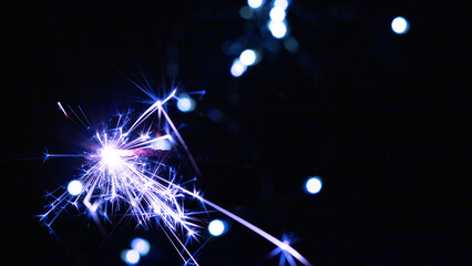 Happy New Year and Merry Christmas, Glittering burning sparkler against blurred bokeh light background