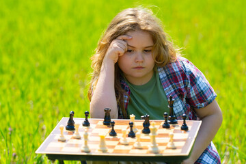 Kid plays chess. A child thinks and playing chess. Kid focuses on chessboard. The kid make...