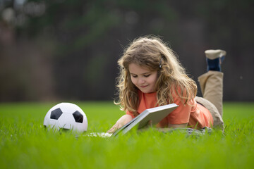 Child reading a book in the grass. Kid enjoying a book story outdoors. Child studying with book in...