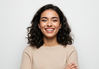 Portrait of a smiling woman with dark curly hair and beige sweater isolated on white background