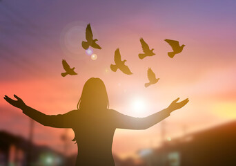 Woman raise hand with dove flying peace sunset
