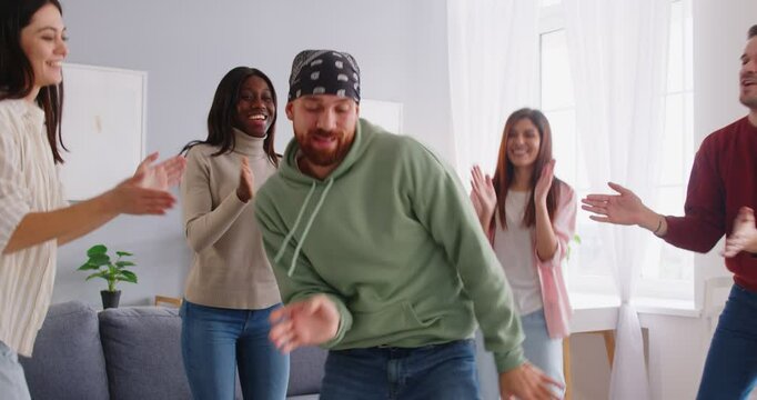 Happy dancing euphoric multiracial best friends group enjoying party at home, people in joy having fun at weekend hanging out, spending free time together in living room, club meeting enjoyment