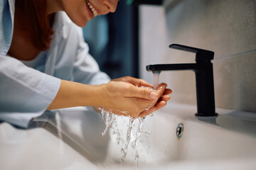 Close up of woman washing her face in bathroom.