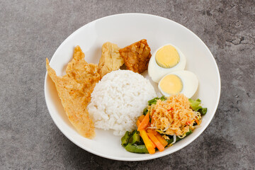Nasi Gudangan, rice served with various vegetable with grated coconut seasoned and various side dishes. Indonesian food
