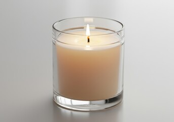 Burning candle in a clear glass holder on a white surface, providing soft light