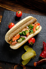 A delicious hot dog with savory sausage, crunchy cucumbers, juicy tomatoes, and onions