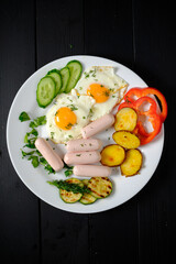 Brightly colored breakfast plate showcases fried eggs, sausages, and fresh vegetables