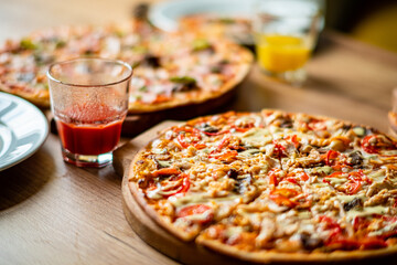 A variety of colorful pizzas is displayed on a rustic wooden table, inviting everyone to enjoy