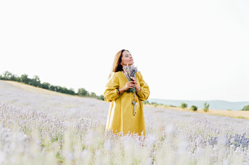 woman in yellow dress stands in lavender field, gently holding bouquet of lavender flowers. She appears serene and contemplative, enjoying beauty and fragrance of blossoms around her.