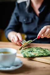 A person enjoys a green omelet and tea, creating a relaxed brunch vibe
