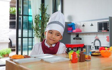 Little boy in chef hat and apron cooking in toy kitchen. Educational toys for young children. Kids play, portrait of Cute little Asian.playing at kitchen at indoor playground