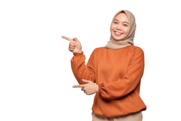 Cheerful young Asian woman in orange shirt pointing fingers at copy space isolated on transparent background