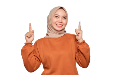 Cheerful young Asian woman in orange shirt pointing finger up at copy space isolated on transparent background