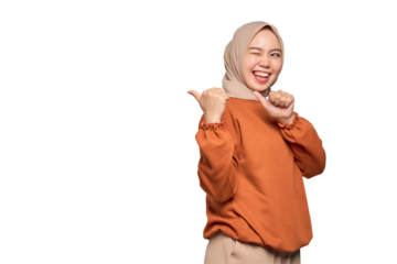 Cheerful young Asian woman in orange shirt pointing fingers at copy space isolated on transparent background