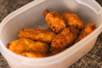 Homemade croquettes stored in a Tupperware container on a kitchen counter