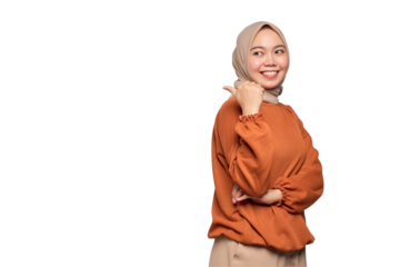 Cheerful young Asian woman in orange shirt pointing fingers at copy space isolated on transparent background