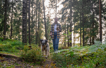 Woman playing with her dog in a lush green forest at sunset