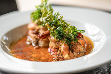 White bowl of shrimp in broth with green garnish