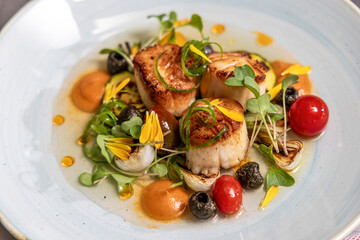 Seared scallops and garnish plated in consommé